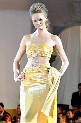 pokaz mody: Eva Minge; modelka w złotej sukni z odkrytymi ramionami